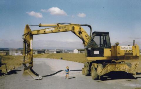 Boy playing underneath scoop of a digger