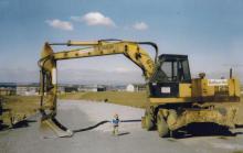 Boy playing underneath scoop of a digger
